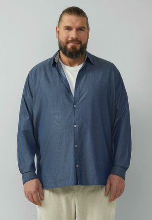 Blaue, langärmlige Button-Down-Bluse mit Kragen, aus einem strukturierten Stoff mit feinem Streifenmuster, kombiniert mit hellen Hosen.