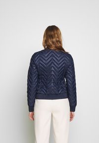 Námořnická prošívaná bunda s vzorem v žebříku, ribbed manžety a páskový spodní lem. Lehký materiál, délka do pasu.