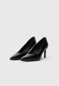 Décolleté in vernice nera con punta affusolata e tacco stiletto sottile. Texture liscia con un design elegante e minimal.