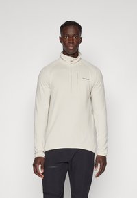 Pullover a mezzo zip di colore beige chiaro con tessuto testurizzato, maniche lunghe e colletto alto. Presenta un piccolo logo sul petto e una tasca con zip.