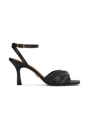 Čierne kožené sandále na vysokom opätku s prekríženým dizajnom na vrchu, nastaviteľným remienkom okolo členka a úzkym, zužujúcim sa opätkom.