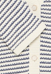 Hvid og marineblå stribet strikket cardigan med cremefarvede sekskantede knapper og ribbede manchetter og kanter.