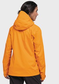 Wasserdichte orange Jacke mit Kapuze, die eine glatte Textur und verstellbare Bundabschlüsse aufweist. Die Rückansicht hebt die Nahtdetails und die Passform hervor.