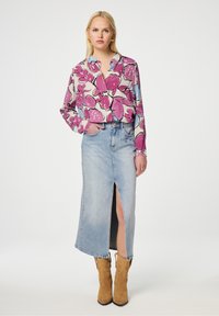 Bloemige blouse in paars en blauw, gecombineerd met een lichtgewassen denim rok met een voorzicht. Gecombineerd met tan cowboystiefels.