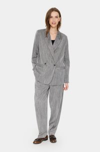 Gray striped suit featuring a double-breasted blazer and loose trousers, with smooth texture and tailored fit. Brown shoes complement the outfit.