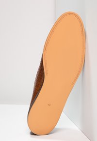 Semelle de chaussure en cuir tressé marron, présentant un dessous lisse couleur beige clair avec des détails de couture et une taille marquée comme 42.