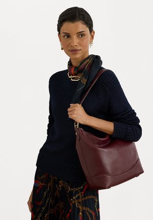 Burgundy leather shoulder bag with a smooth finish, curved shape, and gold-tone hardware, accented by a multicolored patterned scarf.