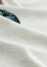 T-shirt in cotone grigio chiaro, con un tessuto testurizzato caratterizzato da pieghe morbide e un dettaglio grafico multicolore sul davanti.