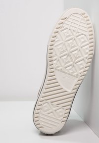White rubber sneaker outsole with textured tread pattern, featuring a diamond shape design and vertical grooves, labeled "Converse All Star."