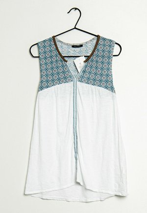 Bezrękawnik z turkusowym wzorzystym karczkiem i białym materiałem poniżej. Ma okrągły dekolt i dekoracyjną lamówkę na krawędziach.