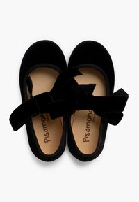 Bailarinas de terciopelo negro con un suave y ancho lazo como acento. Presentan una plantilla suave y acolchada y bordes elasticados para mayor comodidad.