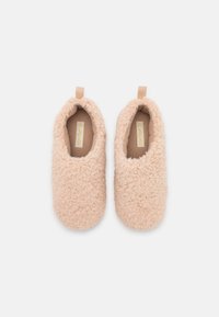 Blush pink slippers made of soft, textured fabric, featuring a round toe and matching pull tab at the heel. Flat, indoor use design.