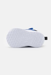 La semelle de chaussure présente une base en caoutchouc gris clair avec un motif texturé, des accents bleus et noirs, et une languette pour un enfilage facile.