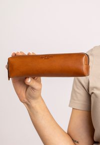 Brauner Lederfedermäppchen mit Reißverschluss, rechteckiger Form und geprägtem Logo. Glatte Oberfläche mit verstärkter Naht entlang der Kanten.