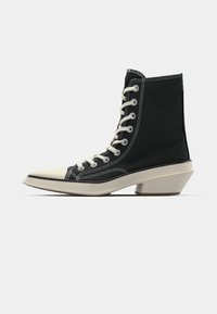 Juodi aukšti drobiniai batai su baltais raišteliais, grietinėlės spalvos pirštuotas dangtis ir išskirtinis kampuotas grietinėlės spalvos kulnas. Siuvinėti akcentai balti.