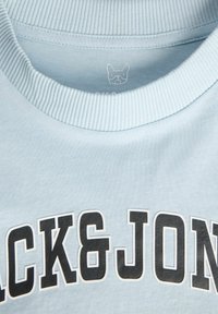 Sudadera azul claro con cuello de canalé, con "BLACK&JONS" en letras negras en negrita. Tejido suave con una textura lisa y un sutil detalle del logo en el interior.