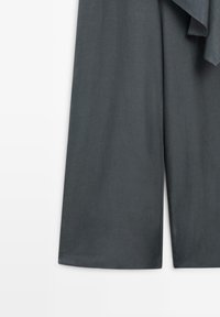 Pantalon gris foncé à jambes larges, coupe ample, raccourci à la cheville, visible de la mi-cuisse à l'ourlet sur fond blanc.