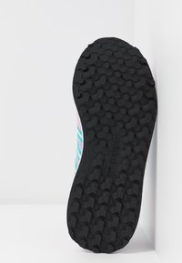 Semelle de chaussure en caoutchouc noir avec motifs hexagonaux antidérapants. La tige présente un design rayé rose clair et turquoise.