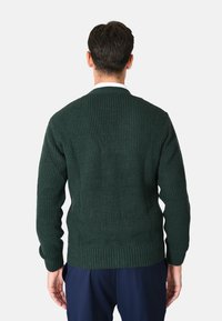 Maglione a coste verde scuro con maniche lunghe e scollo rotondo. Presenta un motivo a maglia strutturata e polsini aderenti con orlo dritto.