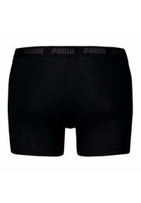 Boxer cortos negros hechos de una tela suave, con una banda elástica amplia que presenta el logo de Puma en un patrón repetido en la parte superior.