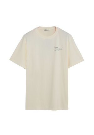 Camiseta de color crema hecha de algodón suave, con cuello redondo y mangas cortas. Texto notable impreso en verde oscuro en la parte frontal.