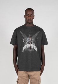 Mørkegrå bomuld t-shirt med et grafisk print af en engel med vinger og teksten "Højere end Himlen" i kontrastfuld hvid.