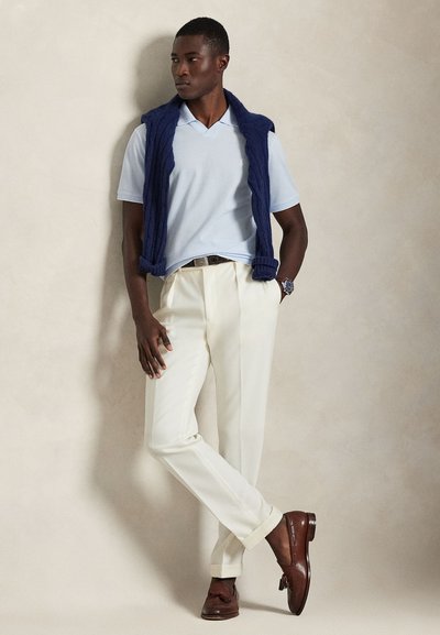 Lys blå polo skjorte kombinert med kremfargede bukser, toppet med en marineblå strikket vest. Brune skinn loafers fullfører antrekket.