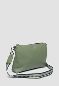Borsa in pelle sintetica verde con chiusura a zip, dotata di una tracolla intrecciata in verde scuro e crema con motivi decorativi.