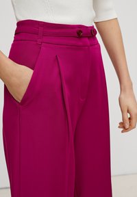 Fuksjowe spodnie o wysokim stanie, z podwójnymi guzikami, plisami i kieszeniami bocznymi. Gładki materiał z delikatnym połyskiem.