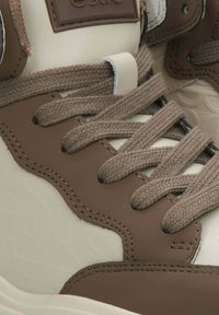 Brązowe i kremowe wysokie sneakersy z fakturowanej skóry, kontrastującymi przeszyciami i plecionymi sznurówkami. Naszywka z logo na języku.