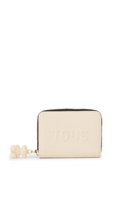 White leather zip-around wallet with embossed "TOUS" logo. Features textured surface and a light-colored bear charm attached.