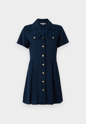 Navy shirt dress with short sleeves, two chest pockets, and gold buttons down the front. A-line silhouette with a pleated skirt.