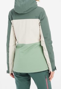 Veste imperméable à blocs de couleur avec un design vert et beige, dotée d'une capuche et de poignets ajustables, vue de dos.