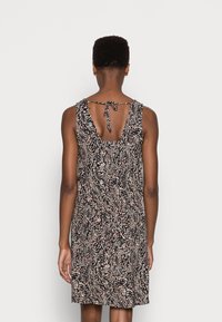 Sukienka bez rękawów w kwiatowy wzór z głębokim dekoltem z tyłu i zawiązywaniem. Kolory obejmują czerń, biel oraz subtelne odcienie różu i niebieskiego.