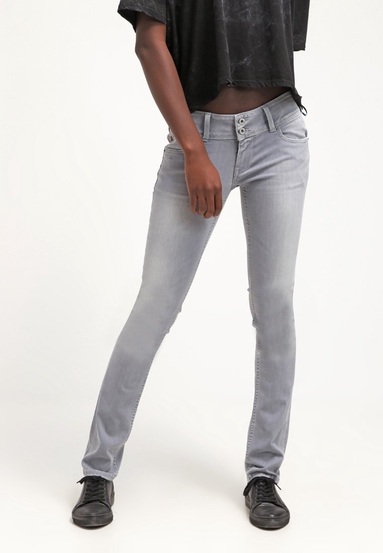 Jeans ajustados grises con un acabado desgastado, que presentan acentos de botones únicos y una textura de tela suave, combinados con zapatillas negras y un top corto.