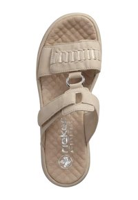 Beige sandaal met een textuur en een gewatteerde voetbed. Kenmerkt zich door dubbele banden, waarvan er één is versierd met een geweven patroon en een ronde metalen accent.