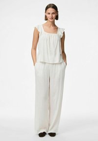 Top in lino bianco con maniche a campana arricciate e scollatura quadrata, abbinato a pantaloni larghi in lino bianco. Design minimalista, vestibilità rilassata.