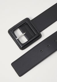 Ceinture en cuir noir avec une boucle en métal carrée, présentant une texture lisse, des coutures précises et plusieurs trous pour l'ajustement.