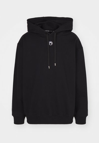 Melna virsjaka ar kapuci, ar priekšējo auklu, ribotām piedurknēm un apakšmalu, un mazu apļveida izšuvumu uz krūšu.