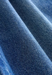 Țesătură din denim într-o nuanță bogată de albastru, cu o textură moale, având un model de țesătură twill proeminent și variații subtile de culoare.