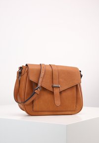 Kahva nahka ristiolkalaukku, jossa on läppäkiinnitys, säädettävä hihna ja sileä pinta. Varustettu hopeanvärisillä yksityiskohdilla.