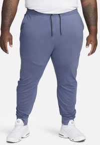 Blauwe sportieve joggingbroek van zacht materiaal, met zijzakken, een verstelbare trekkoord tailleband en toelopende enkels.