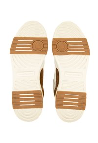 Brūni un krēmkrāsas sporta apavu zoles ar teksturētu gumiju. Iezīmējas horizontāliem rievām un apļveida akcentiem. Redzama "Sergio Tacchini" zīmola identifikācija.