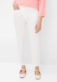 Witte broek met een recht beenontwerp, voorzien van voorzakken en een knoopsluiting. Gepaarde met lichtgekleurde platte schoenen.