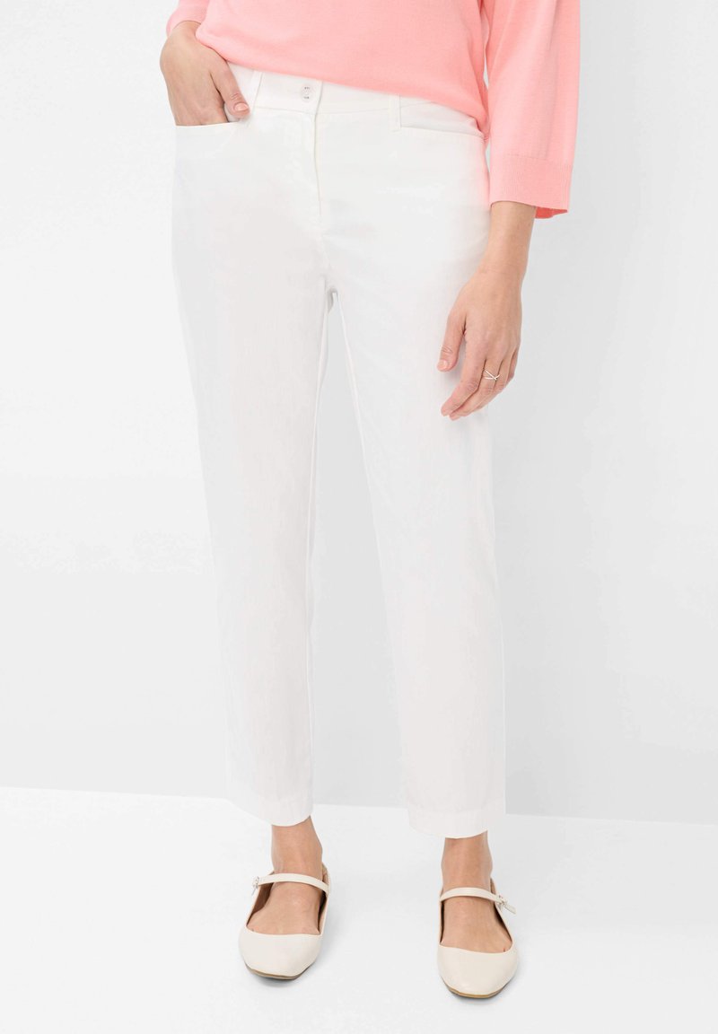Witte broek met een recht beenontwerp, voorzien van voorzakken en een knoopsluiting. Gepaarde met lichtgekleurde platte schoenen.