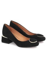 Décolleté in suede nero con tacco a blocco, punta arrotondata, accento circolare dorato sulla tomaia e un morbido interno in pelle. Suola nera uniforme.