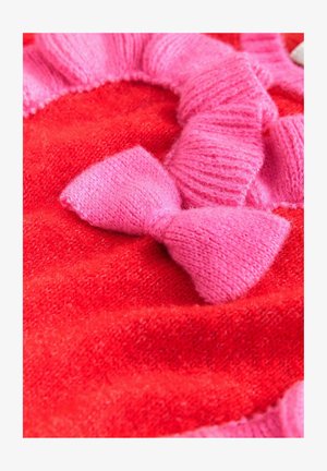 Roter Strickstoff mit weicher Textur, verziert mit einem rosa Rüschensaum und zwei rosa gestrickten Schleifen. Das Design ist nahtlos und lebendig.