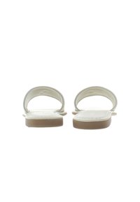 White slip-on sandals with a smooth upper, rounded straps, and a flat sole. Textured footbed with a subtle logo detail.