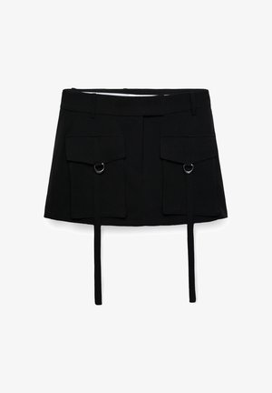 Mini-jupe noire avec deux grandes poches avant à rabat, chacune ornée d'un anneau métallique et de longues sangles pendantes.