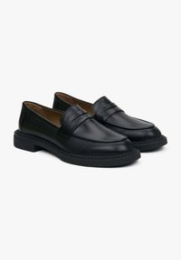 Black leather loafers with a rounded toe, decorative stitching, and a small block heel. Smooth texture with a slip-on design and accent details.